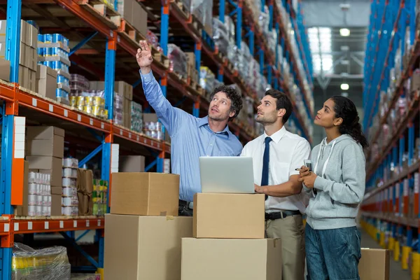 Warehouse manager and workers discussing with laptop — Stock Photo, Image