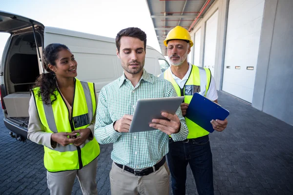 Manager and warehouse workers discussing with tablet — ストック写真