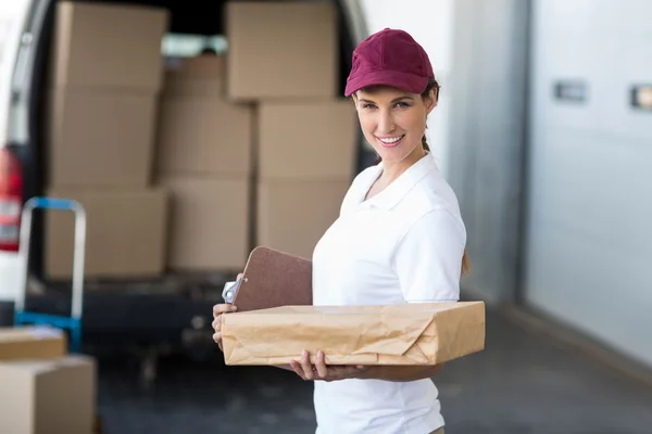 Delivery woman holding clipboard and parcel — Stockfoto