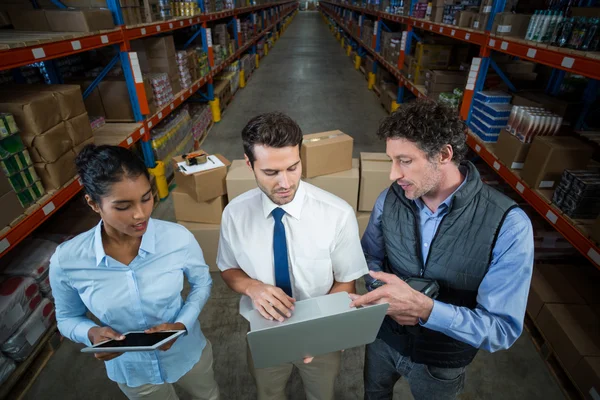 Warehouse workers and manager discussing with laptop — Stock Photo, Image