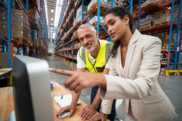 Warehouse manager and worker discussing with computer — ストック写真