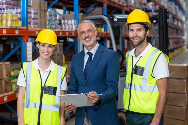 Warehouse manager and co-workers standing with clipboard — Stock Photo, Image