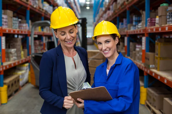Warehouse manager and worker discussing with clipboard — Stock Photo, Image