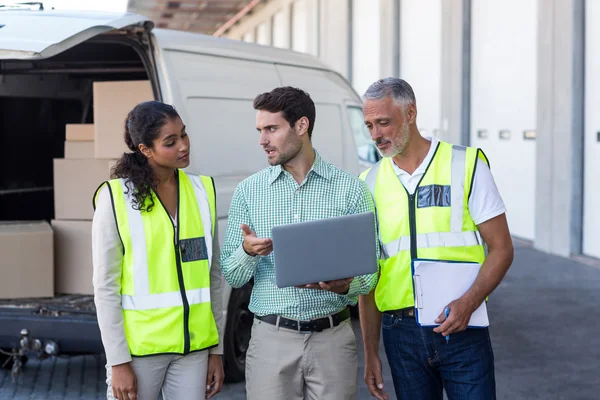 Manager and warehouse workers discussing with laptop — ストック写真