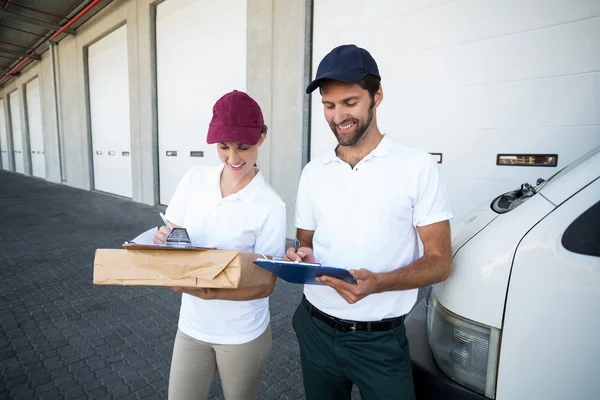 Delivery man and woman writing on clipboard — ストック写真