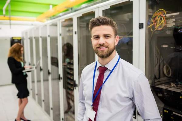 Technika uśmiechający się stojąc w serwerowni — Zdjęcie stockowe