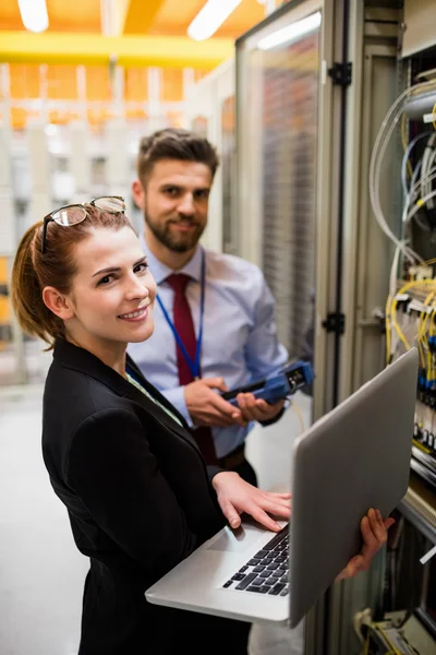 Technici, die laptop gebruiken bij het analyseren van de server — Stockfoto