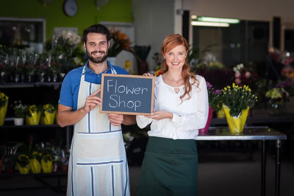 Couple holding slate with flower shop — Stockfoto