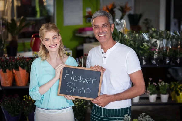 Bloemisten houden bloem winkel teken — Stockfoto