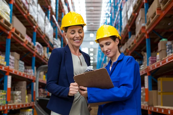 Warehouse manager and worker discussing with clipboard — Stock Photo, Image