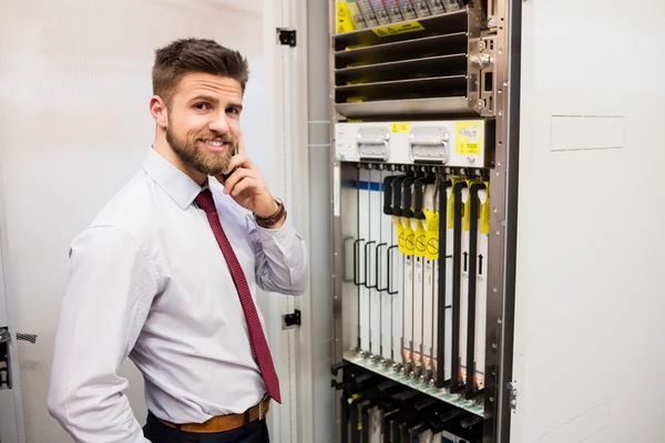 Technician talking on mobile phone in server room — Stock Photo, Image