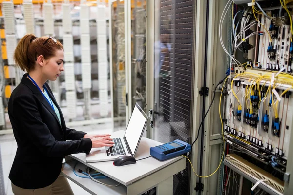 Technician using laptop while analyzing server — ストック写真