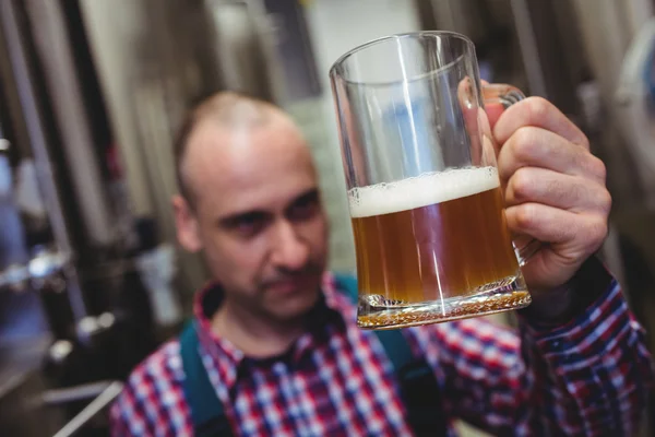 Trabajador examinando cerveza en taza — Foto de Stock