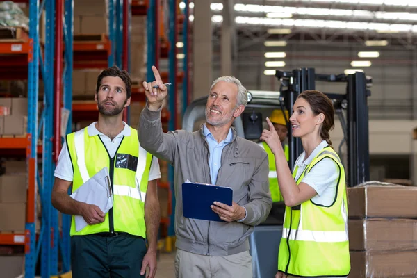 Warehouse manager and workers discussing with clipboard — Stockfoto