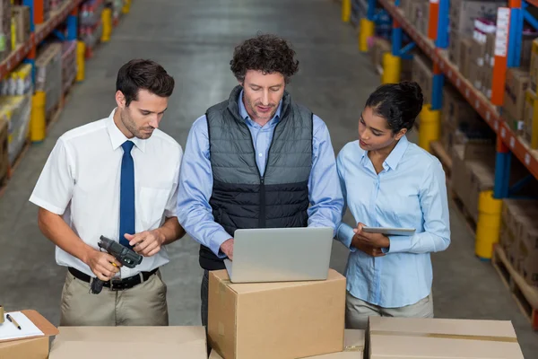 Warehouse workers and manager discussing with laptop — Stock Photo, Image
