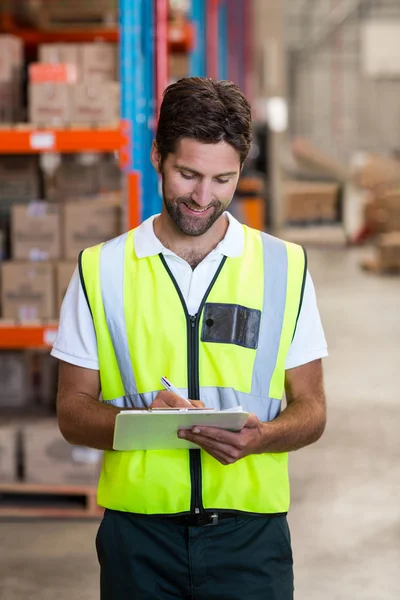 Warehouse worker writing on clipboard — Stock Photo, Image