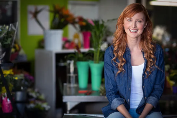 Florist sitting on table in flower shop — Stock fotografie