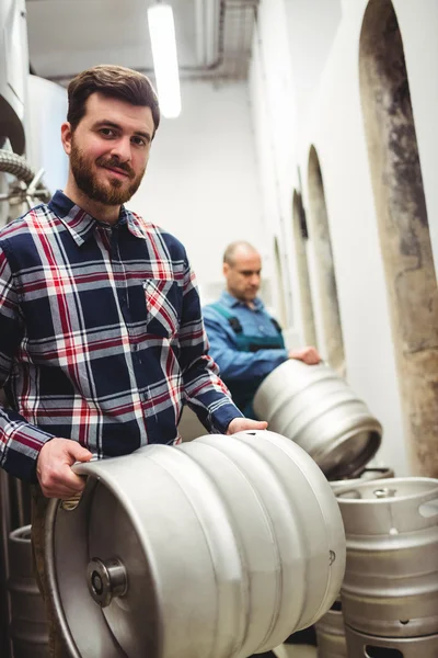 Confident owner carrying kegs at brewery — Stock Photo, Image