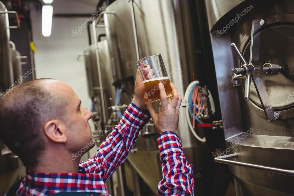 Brewery worker inspecting beer in glass Stock Photo by ©Wavebreakmedia