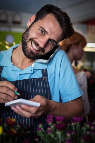 Male florist taking order on phone — Stock fotografie