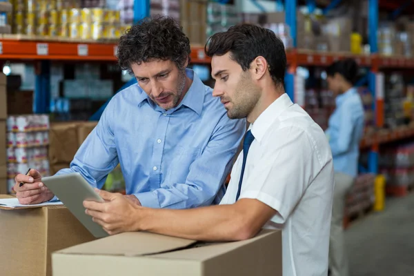 Warehouse workers discussing with digital tablet — Stockfoto