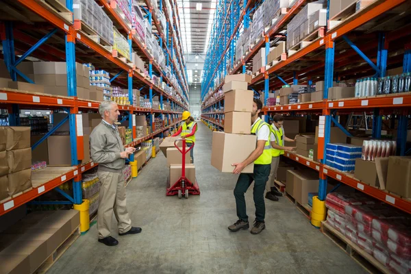 Gerente mirando a los trabajadores que llevan cajas — Foto de Stock
