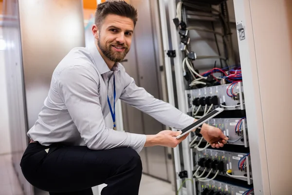 Technician using tablet while analyzing server — ストック写真