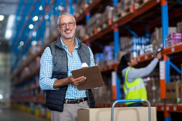 Gerente de almacén sonriendo y sujetando el portapapeles — Foto de Stock