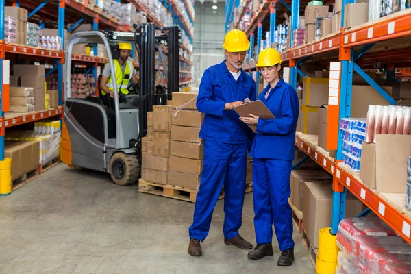 Warehouse workers discussing with clipboard — Stock Photo, Image