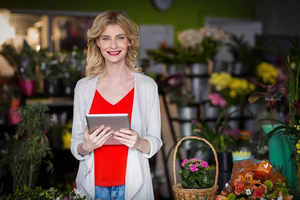 Fiorista che tiene compressa in negozio di fiori — Foto Stock