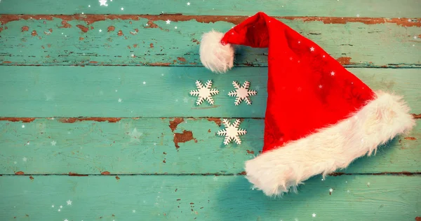 Santa čepice a sněhová vločka na dřevěné prkno — Stock fotografie