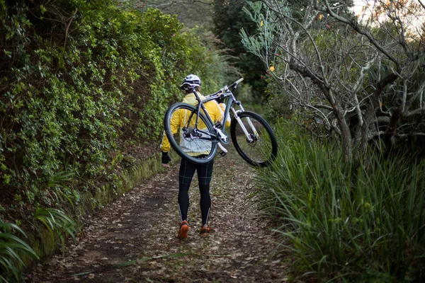 Motociclista transportando bicicleta de montanha e caminhando — Fotografia de Stock