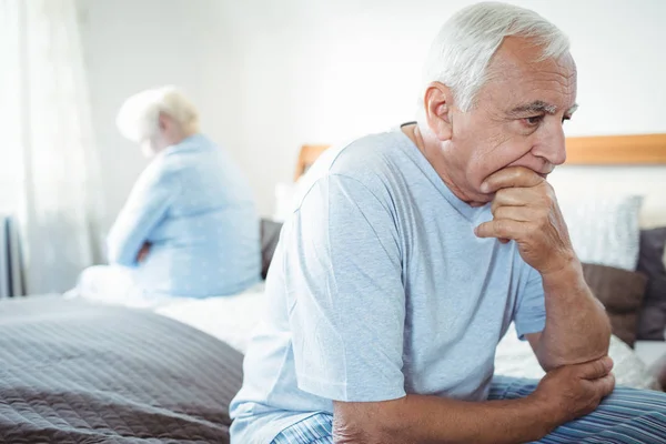 Sad senior couple sitting on bed — Stock Photo, Image