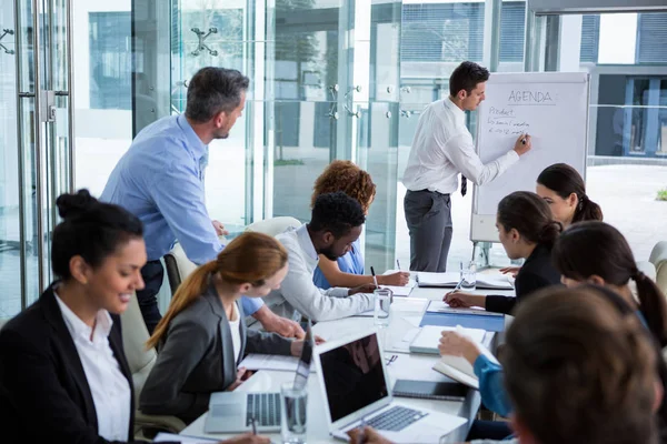 Geschäftsmann diskutiert am Whiteboard mit Mitarbeitern — Stockfoto