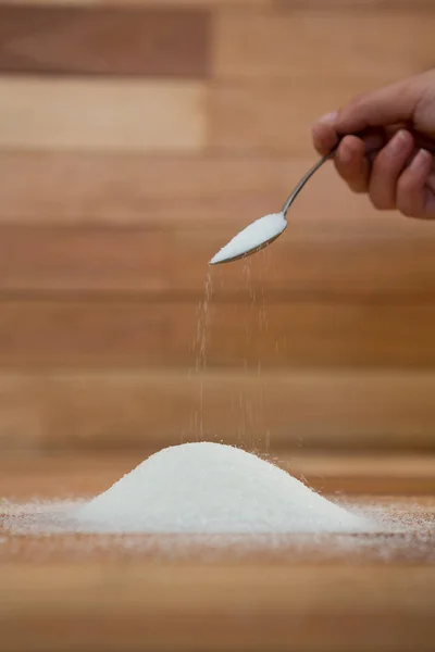Woman hand pouring sugar from spoon — Stock Photo, Image