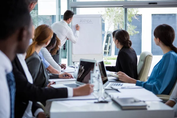 Geschäftsmann diskutiert am Whiteboard mit Mitarbeitern — Stockfoto