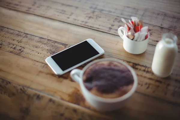 Kaffekopp med telefon och mjölk flaska — Stockfoto