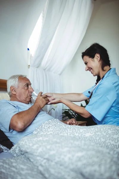 Sjuksköterskan ger ett glas vatten till senior mannen — Stockfoto