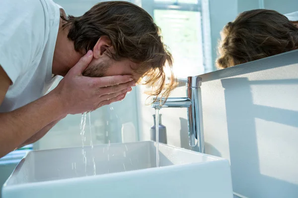 Hombre lavándose la cara con agua en el baño —  Fotos de Stock