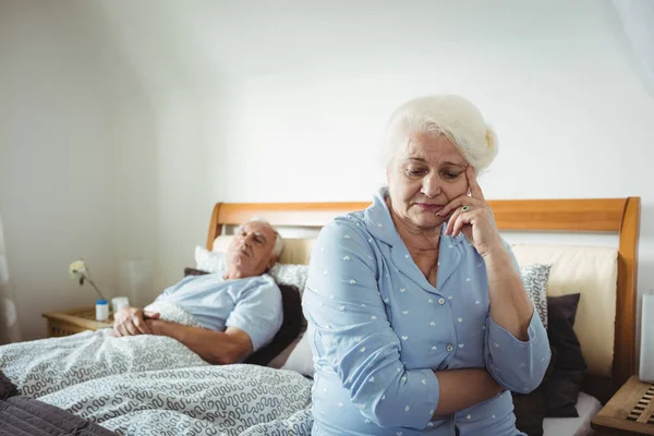 Oroliga äldre kvinna sitter på sängen — Stockfoto