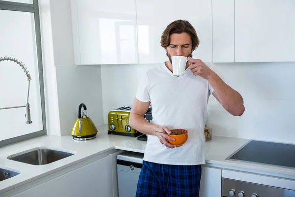 Uomo che beve caffè mentre fa colazione — Foto Stock