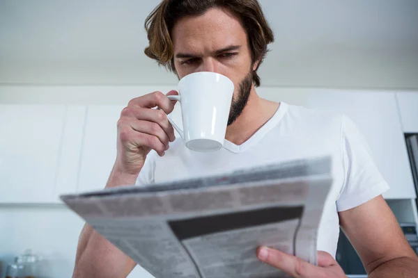 Uomo che legge il giornale mentre prende un caffè — Foto Stock