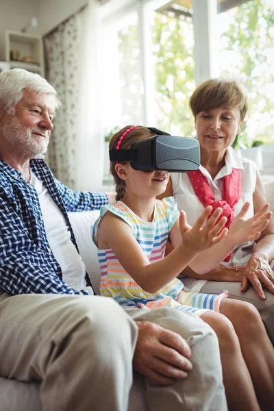 Barnbarn med virtuell verklighet headset med hennes morföräldrar i vardagsrum — Stockfoto