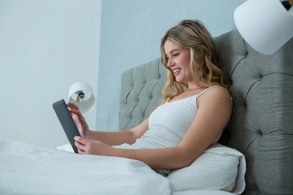 Kobieta za pomocą cyfrowego tabletu na łóżku — Zdjęcie stockowe