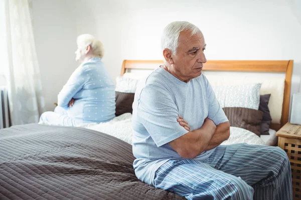 Trauriges Seniorenpaar sitzt auf Bett — Stockfoto