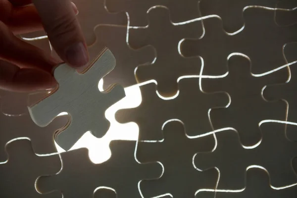 Woman placing missing piece in Jigsaw puzzle — Stock Photo, Image