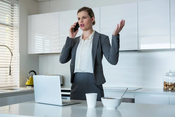 Mujer hablando por teléfono móvil en la cocina —  Fotos de Stock