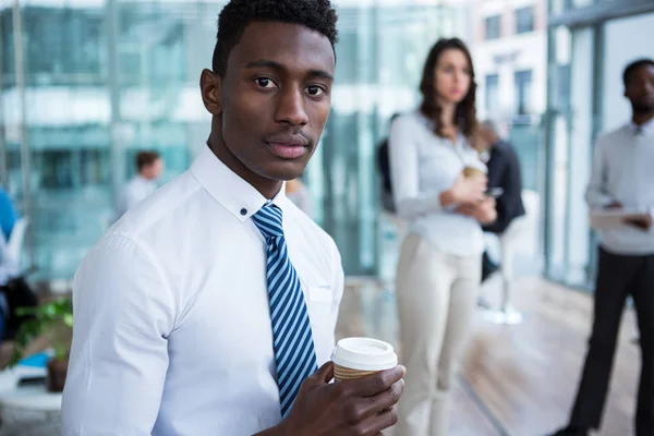 Businessman holding coffee in office — Stock Photo, Image