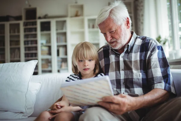 Senior man and her granddaughter looking at a photo album — Stock Photo, Image