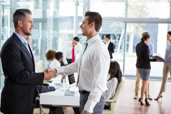 Businessmen shaking hands in office — Stock Photo, Image